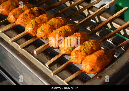 Thai salsa speziata torta di pesce grill sul legno di bambù, il fuoco selettivo Foto Stock