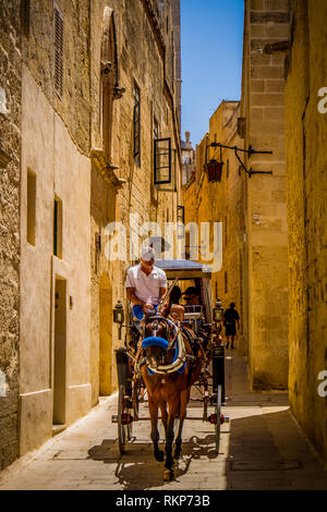 Cavallo e Carrozza in una stretta strada di Mdina, Malta in una giornata di sole Foto Stock