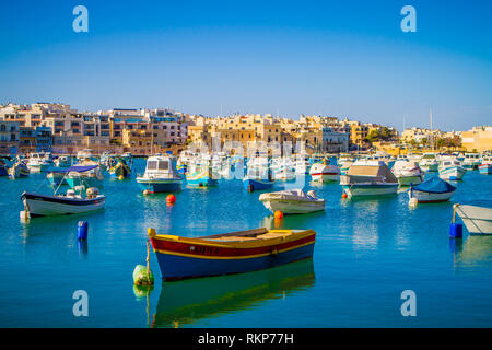 Barche colorate nel piccolo villaggio di pescatori di Marsaxlokk, porto di Malta in una giornata di sole Foto Stock