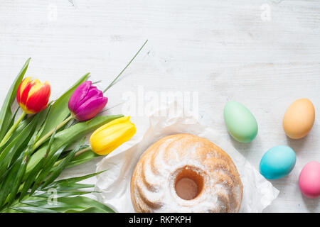 Pasqua Primavera colorati tulipani con palm croce torta e uova decorazione su legno bianco sfondo naturale Foto Stock