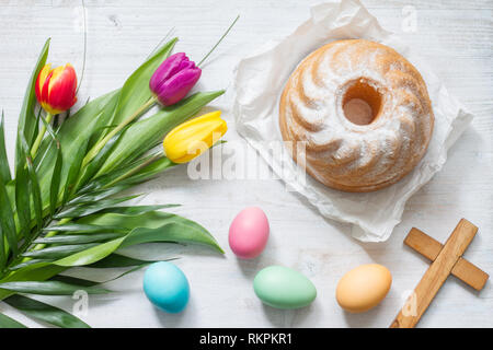 Pasqua Primavera colorati tulipani con palm croce torta e uova decorazione su legno bianco sfondo naturale Foto Stock