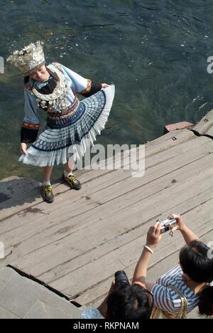 Un turista vestito in abiti Miao per avere la sua fotografia scattata in Fenghuang. Significato 'Phoenix' in cinese, Fenghuang è stato chiamato dopo il mitico uccello Foto Stock