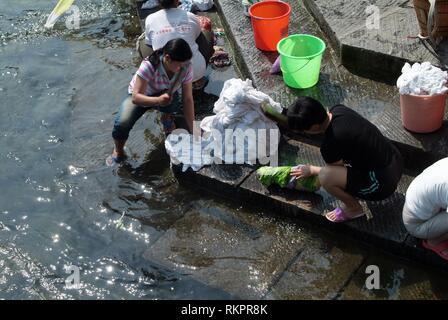 La gente del posto il lavaggio di biancheria e abiti in Tou Jiang River a Fenghuang. Significato 'Phoenix' in cinese, Fenghuang è stato chiamato dopo il mitico uccello di imm Foto Stock