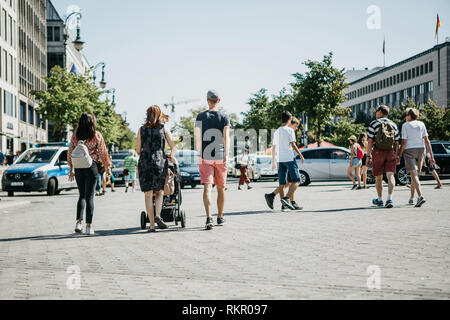 Germania, Berlino, 05 Settembre 2018: una giovane coppia con un bambino in un passeggino e altre persone a piedi giù per la strada per le loro attività quotidiane. Foto Stock