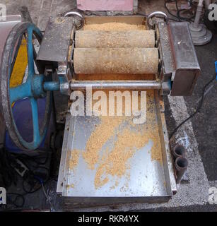 Un mercato in stallo utilizza un azionata a mano vintage frantumatore di arachidi per rendere caramella di arachidi Foto Stock