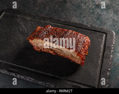 Arrosto di maiale barbecue nervature sul nero ardesia tagliere Foto Stock