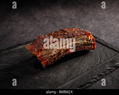 Grigliata di carne di maiale barbecue nervature su un nero ardesia tagliere Foto Stock