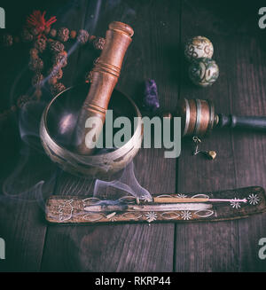 Il rame Singing Bowl e un bastone di legno su una tabella di colore marrone Foto Stock