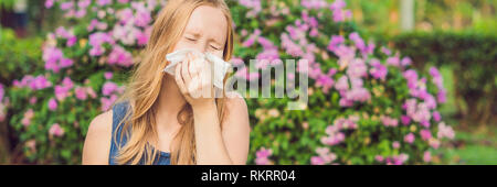 Allergia da polline concetto. Giovane donna sta per starnutire. Alberi fioriti in background banner, formato lungo Foto Stock