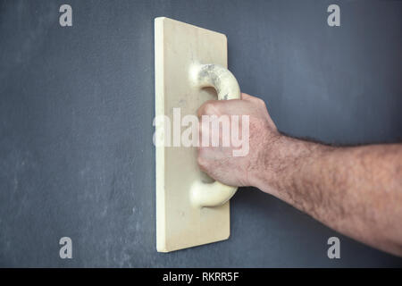 I lavoratori di mano con una cazzuola smussatura di una parete con intonaco decorativo Foto Stock