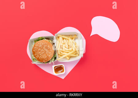 Io amo il fast food. Le patatine fritte Burger in forma di cuore isolato su sfondo rosso. Nutrizione malsano concetto. Composizione concettuale con copyspace Foto Stock