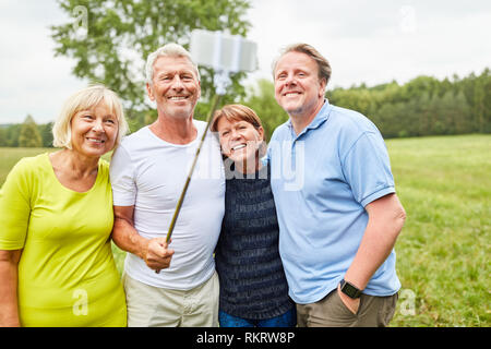 Gruppo di anziani come amici prendere un selfie con lo smartphone su selfie stick Foto Stock