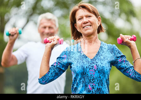 Attivo coppia senior facendo forza di formazione con manubri in riabilitazione in natura Foto Stock