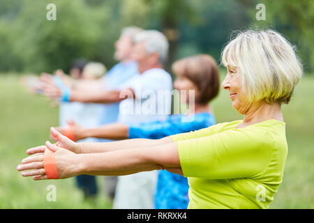 Seniors attivi in rehab esercitano con la fascia elastica nella fisioterapia Foto Stock