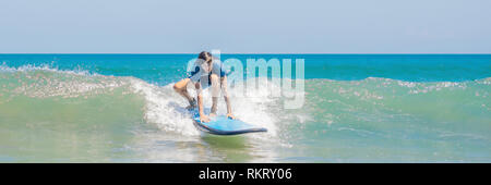 Il giovane principiante Surfer impara a navigare su una schiuma di mare sull'isola di Bali banner, formato lungo Foto Stock