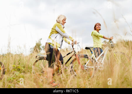 Due senior donne andare su un giro in bici nella natura insieme Foto Stock