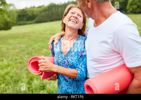Di vitale importanza coppia senior passa per una passeggiata nel parco con tappeti di esercizio Foto Stock
