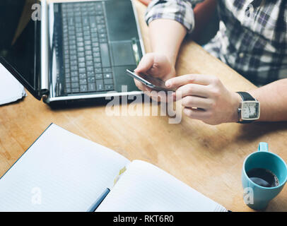 Area di lavoro design studio ufficio. Vista superiore della scrivania con computer portatile, un notebook e una tazza di caffè. Primo piano di business man lavorando sul suo progetto utilizzando mo Foto Stock
