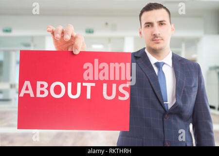 Messa a fuoco selettiva immagine dell uomo d affari presentando carta rossa con chi siamo il testo come pubblicità informazioni essenziali di concetto Foto Stock