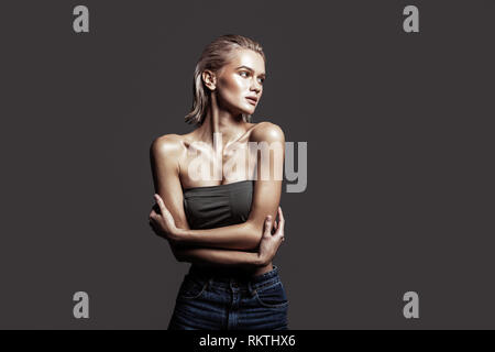 Slim donna che indossa jeans e breve top in posa professionalmente Foto Stock