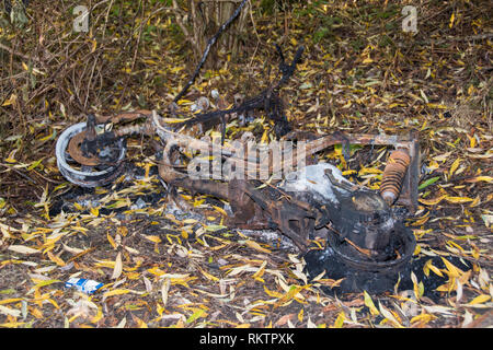 Sheffield, UK: Ott 20 2016: Un bruciata vecchio arrugginito ciclomotore abbandonato nei boschi accanto al percorso di foresta in cui è stato impostato sul fuoco, nel burrone Woodthorpe Foto Stock