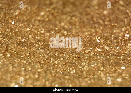 Golden glitter texture con riflessi di luce, defocalizzata golden glitter con sfondo bokeh effetti Foto Stock