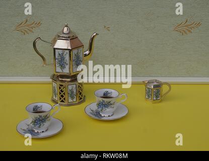 Tè per due, inglese teacups, piattini, placcati argento teiera su una stufa di argento, crema brocca con decorazioni floreali Foto Stock