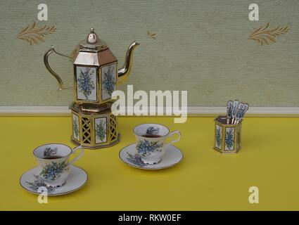 Tè per due, inglese teacups, piattini, placcati argento teiera su una stufa di argento, vaso cucchiaio e cucchiaino, con decorazioni floreali Foto Stock