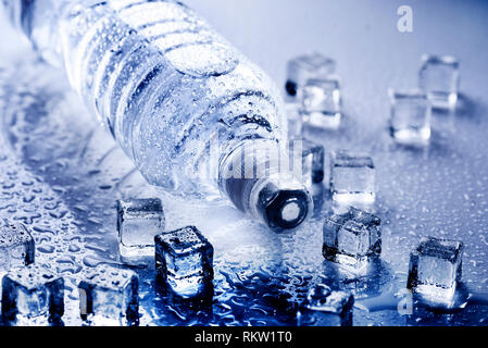 Fresca da bere acqua minerale in bottiglia di plastica con cubetti di ghiaccio e gocce ghiacciate. Uno stile di vita sano concetto. Foto Stock