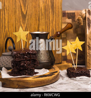 Una pila di square brownie pezzi versata con il cioccolato su una tavola di legno. Deliziosi dessert Foto Stock