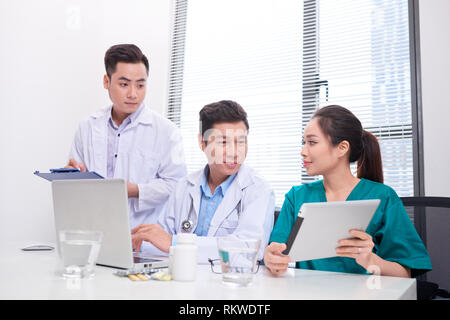 Il gruppo di medici e infermieri esaminando referto medico del paziente. Team di medici che lavorano insieme su file di pazienti in ospedale. Foto Stock