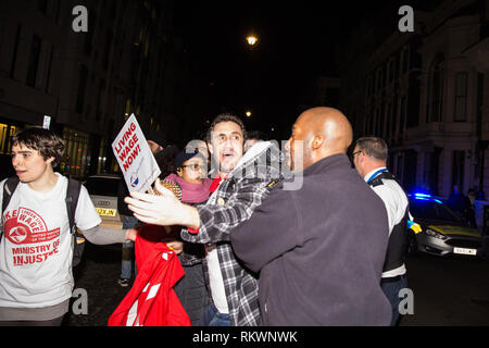 Londra, Regno Unito. 12 Feb, 2019. Un funzionario di polizia spinge Petros Elia, segretario generale del progetto grassroots sindacato United voci del mondo, al di fuori della strada durante una manifestazione di protesta al di fuori di un edificio in Pall Mall dove la giustizia Segretario David Gauke stava ospitando un aperitivo contro il suo rifiuto di pagare il vivere a Londra in termini di salari e di concedere un congedo annuale e malati pagare per pulitori, guardie di sicurezza e gli addetti alla reception il lavoro presso il Ministero della giustizia, tutti dei quali sono in sciopero di recente. Credito: Mark Kerrison/Alamy Live News Foto Stock