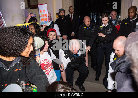 Londra, Regno Unito. 12 Feb, 2019. Un funzionario di polizia spinge un membro del progetto grassroots sindacato United voci del mondo a protestare al di fuori di un edificio in Pall Mall dove la giustizia Segretario David Gauke stava ospitando un aperitivo contro il suo rifiuto di pagare il vivere a Londra in termini di salari e di concedere un congedo annuale e malati pagare per pulitori, guardie di sicurezza e gli addetti alla reception il lavoro presso il Ministero della giustizia, tutti dei quali sono in sciopero di recente. Credito: Mark Kerrison/Alamy Live News Foto Stock