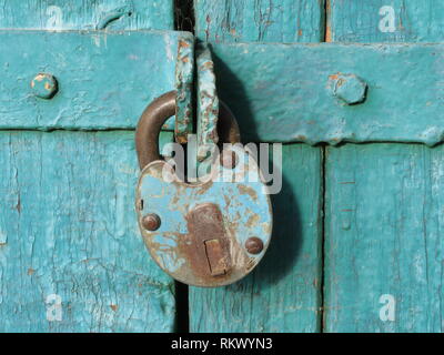 Vecchio lucchetto arrugginito sul verde di porte in legno. Bloccati i cancelli, home concetto di sicurezza Foto Stock