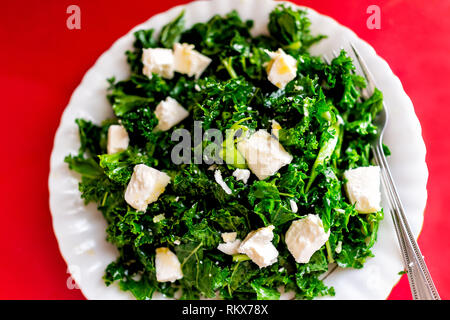 Flat Top closeup di cavolo bianco formaggio feta verde vegetariano vegano insalata in ristorante con piastra forcella sulla tabella rossa Foto Stock