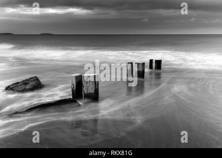 La marea in uscita su Youghal stran come thw sole tramonta dietro di me e le nuvole scure in rotolo. Foto Stock