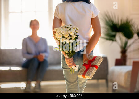 Vista posteriore al kid figlia azienda fiori e confezione regalo Foto Stock