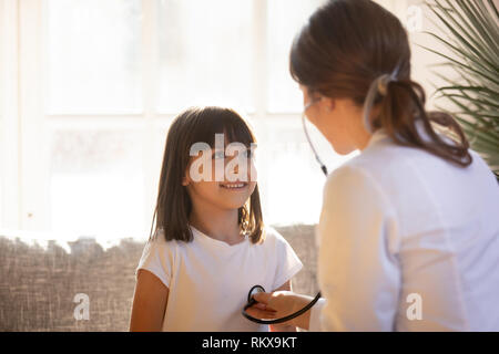 Carino kid femmina visita medico pediatra tenendo uno stetoscopio esaminando bambino Foto Stock