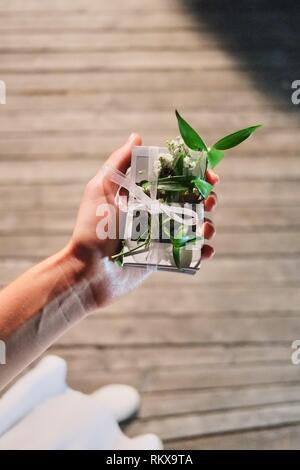Mani femminili tenere la confezione regalo di foto. Vista da sopra. Avvolgimento di sfondo di festa. Foto Stock