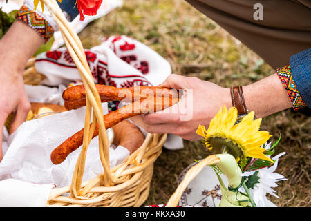 Il Russo Ortodosso Ucraino benedizione pasquale in vimini cesto di paglia con la persona che effettua la salsiccia di carne al di fuori della chiesa con fiori Foto Stock