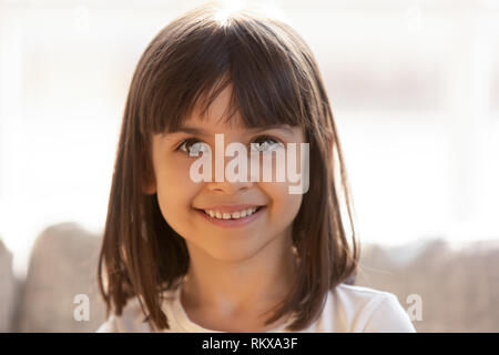 Incantevole piccola ragazza sorridente guardando la fotocamera in luoghi chiusi, headshot ritratto Foto Stock