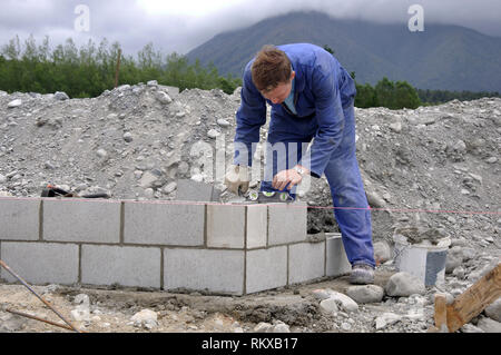Posizioni di builder blocchi nella parete di cemento Foto Stock