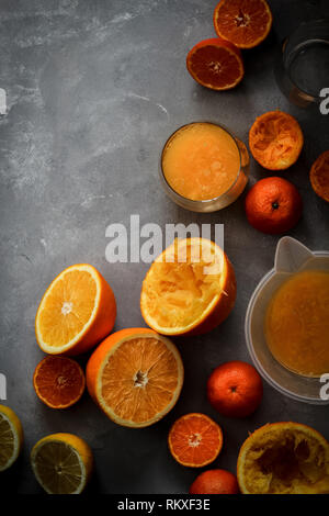 Lay piatto con fette di agrumi e spremuta fresca su uno sfondo scuro, verticale Foto Stock