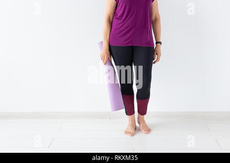 Yoga, uomini concetto - Close up della donna azienda mat dopo una lezione di yoga su sfondo bianco con spazio di copia Foto Stock