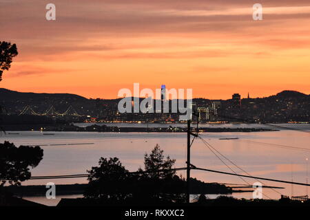 San Francisco Bay Bridge e l'Isola del Tesoro durante il tramonto con una linea di alimentazione in primo piano. Preso da El Cerrito, CA. Foto Stock