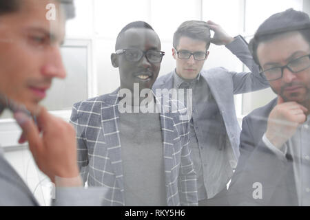 Dietro il vetro. Il team aziendale è il pensiero di idee per un nuovo progetto Foto Stock