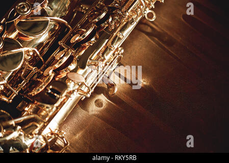 Close up e la visualizzazione dettagliata di un lucido chiavi di un golden sassofono sdraiato sul divano in pelle. Strumenti musicali. Attrezzature musicali. Musica classica Foto Stock