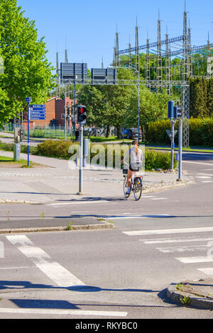 Giovane donna in bicicletta a un attraversamento pedonale su una strada di città Foto Stock