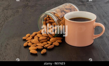 Mandorle riversando fuori del vasetto in vetro con caffè Foto Stock