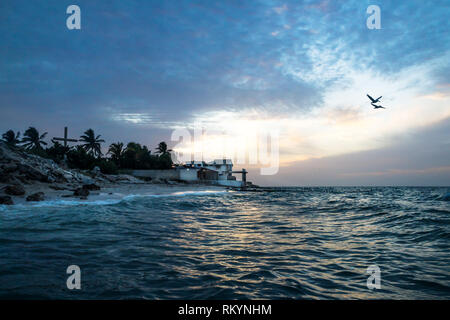 Tramonto con pellicani lungo la costa con spiaggia e case di Chelem, Messico Foto Stock